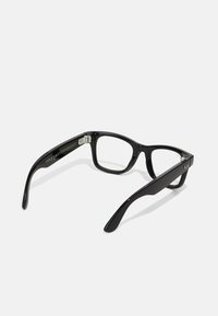 Lunettes de vue rectangulaires noires avec des verres transparents et des branches épaisses, montrant la charnière et le logo de la marque sur la branche, sur fond blanc.