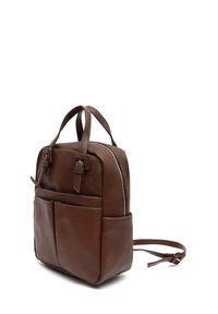 Sac à dos en cuir brun avec des sangles réglables, deux poignées, fermeture éclair et deux poches avant. Texture lisse et forme rectangulaire compacte.