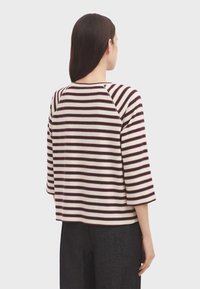 Sweter w kolorze bordowym i kremowym w paski, z rękawami raglanowymi o długości trzy czwarte, o prostokątnym kształcie i okrągłym dekolcie. Minimalistyczny design, miękka tekstura.