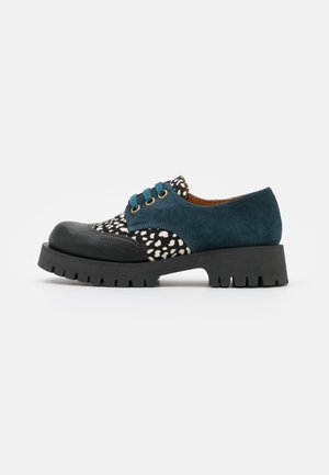 Buty na sznurowadła z czarnym skórzanym noskiem, tkaniną w czarno-białe cętki, bokami z turkusowego zamszu oraz grubą czarną gumową podeszwą z głębokim bieżnikiem.