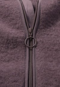 Lila Fleece-Kleidungsstück mit einem Reißverschluss. Verfügt über eine texturierte Oberfläche und einen silbernen Reißverschluss mit einem runden Ring-Akzent.