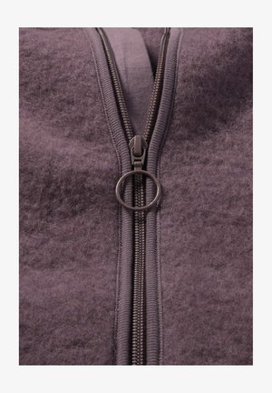 Lila Fleece-Kleidungsstück mit einem Reißverschluss. Verfügt über eine texturierte Oberfläche und einen silbernen Reißverschluss mit einem runden Ring-Akzent.