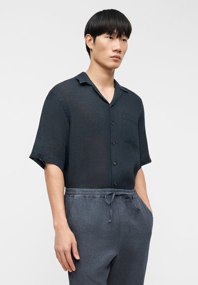 Chemise en lin bleu foncé à manches courtes avec une patte de boutonnage, un col cranté et une poche poitrine, associée à un pantalon à cordon de serrage assorti.