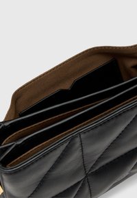 Czarny skórzany portfel z pikowanym wzorem, wyposażony w liczne przegrody i brązowe zamszowe wnętrze. Zawiera kieszonkę na karty.