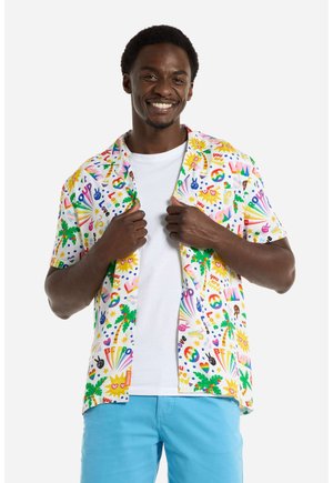 Korte mouwen shirt in het wit met een kleurrijke print van vredessymbolen, palmbomen en hartmotieven. Gedragen over een eenvoudig wit T-shirt.
