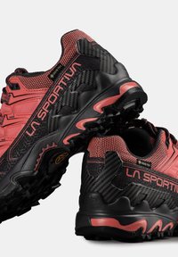 Černé a růžové běžecké boty na trail s texturovaným svrškem, uhlíkovými akcenty a robustní podrážkou s výraznými vzory, označené "LA SPORTIV."