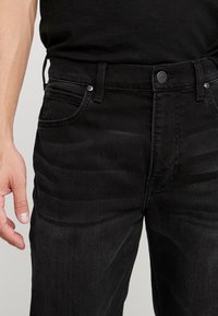 Černé džíny z denimu se střihem do rovného nohavice, s knoflíkovým zapínáním, pěti kapsami a jemnými detaily blednutí na látce.