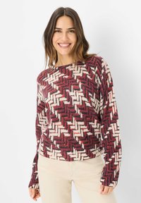Maglione lavorato a maglia con motivo a zigzag in bordeaux, crema e nero. Collo rotondo e maniche lunghe con vestibilità comoda.