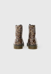 Stivaletti alla caviglia con stampa leopardata e finitura lucida, suole nere e superficie texturizzata. Dettaglio con zip sul retro per una facile indossabilità.