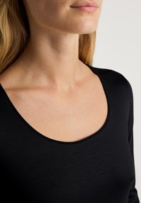 Zwarte lange mouw top met een ronde halslijn, gemaakt van gladde stof. Heeft een aansluitend ontwerp dat zich naar het lichaam vormt.