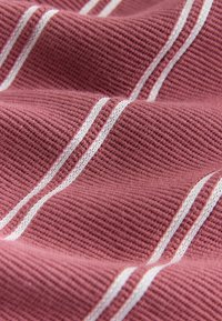Textília v tmavo ružovej farbe s bielymi pruhmi, ktorá má žebrovanú textúru vytvárajúcu hĺbku a rozmer vo vzhľade látky.