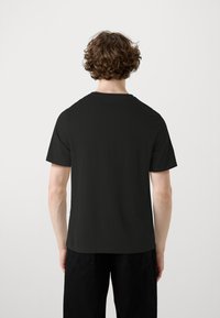 T-shirt nera a maniche corte con scollatura rotonda, realizzata in tessuto leggero, con una texture liscia e una vestibilità rilassata.