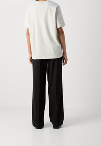 Szara bawełniana koszulka z krótkim rękawem, luźny krój i okrągły dekolt, zestawiona z czarnymi spodniami o wysokim stanie i szerokiej nogawce.