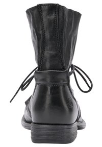 Bottine en cuir noir avec une finition texturée, semelle plate, et lacets noués à l'arrière, arborant un accent logo rond sur le côté.