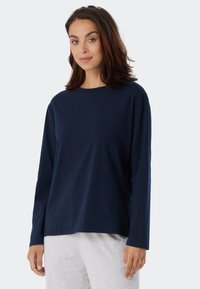 Marinblus med lång ärm i mjuk bomull, rund halsringning och avslappnad passform, kompletterad med en slät textur och minimalistisk design.