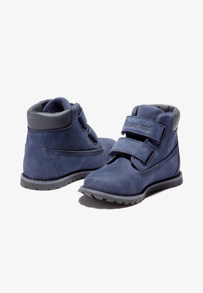 Paire de bottines bleues pour enfants avec double bride velcro et cols noirs rembourrés, semelles légères à relief, logo Timberland sur les brides.