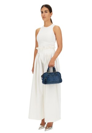 Borsa a mano blu in pelle con manici doppi, forma rettangolare e tasca anteriore. Indossata con un top senza maniche bianco e pantaloni bianchi a vita alta.