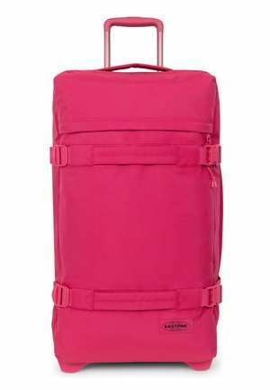 Sac de voyage rose vif à roulettes avec poignée rétractable, sangles de compression latérales et logo Eastpak dans le coin inférieur avant.