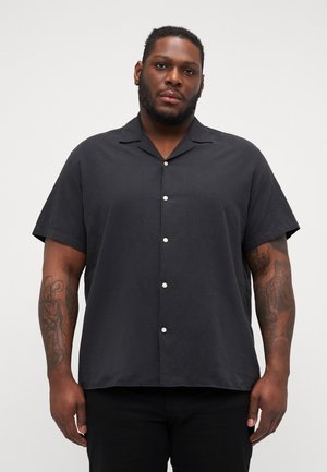 Chemise à manches courtes noire avec fermeture à boutons, fabriquée en tissu léger. Elle présente un col camp et un subtil éclat, avec des boutons blancs et une coupe décontractée.