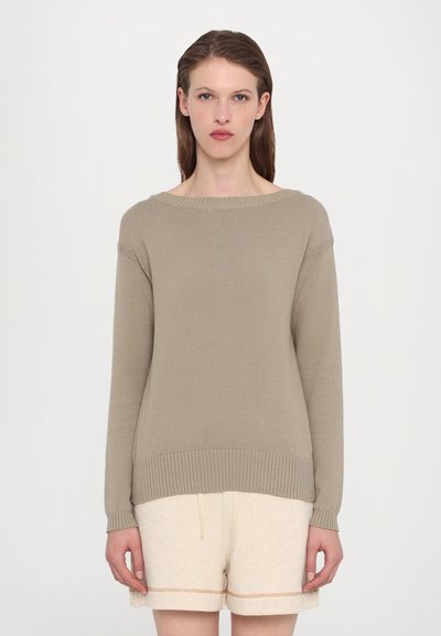 Beige gebreide trui met een brede off-shoulder halslijn en een geribbelde zoom, gecombineerd met lichtbeige shorts met een subtiele naaddetail.