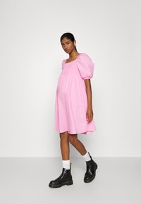 Vestido rosa com mangas bufantes e decote quadrado, corpete justo e saia solta, combinado com botins pretos e meias brancas.