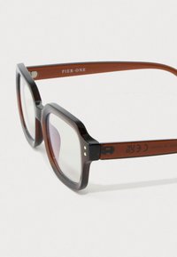 Obdĺžnikové tmavé tortoise shell rámy okuliarov s priehľadnými šošovkami, značeny "Pier One" na hnedom vnútornom ramene.