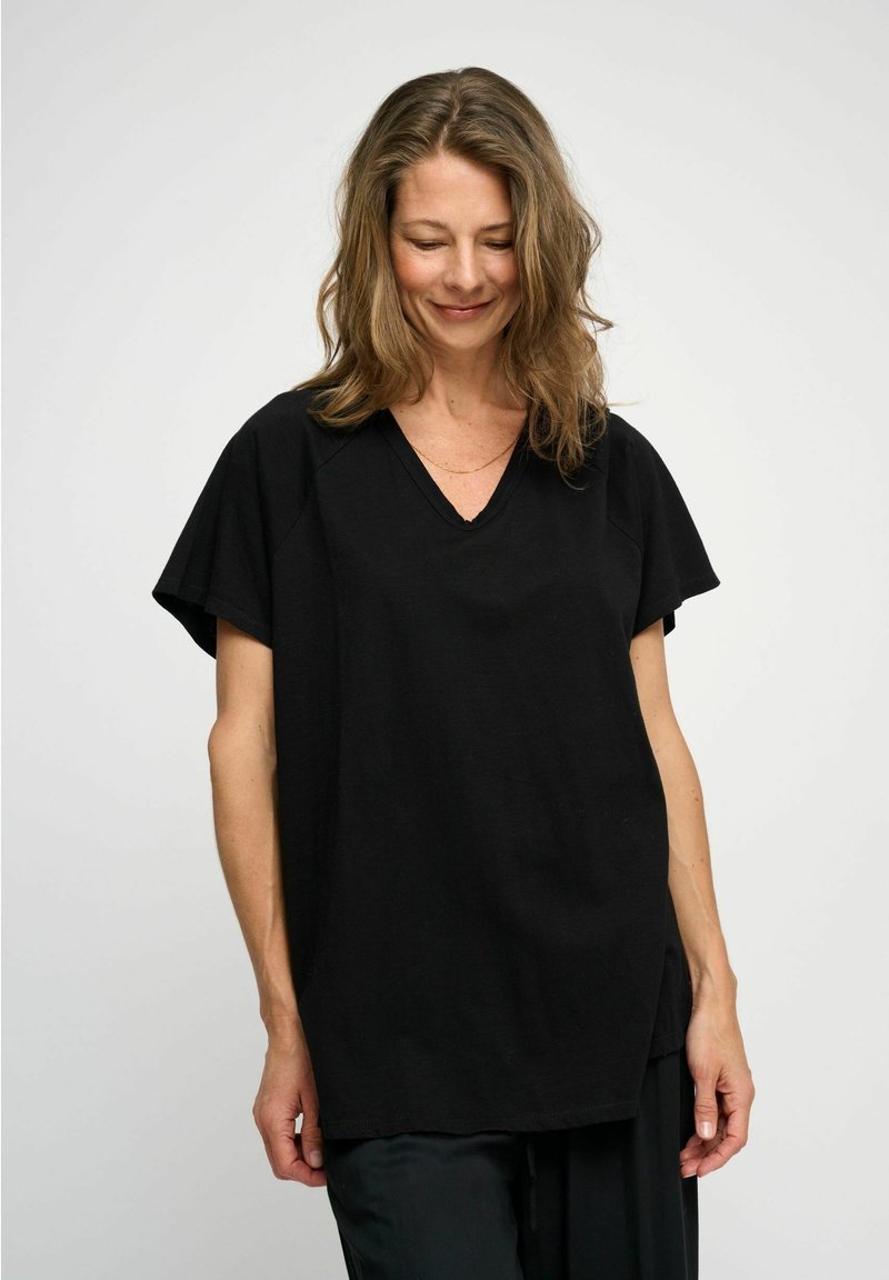 Black oversized V-neck t-shirt, short sleeves, soft texture, relaxed fit, side slits, and a smooth, minimal design.