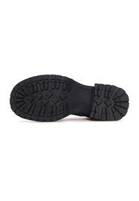 Suela de bota de goma negra con patrones de banda de rodadura profundos y multidireccionales, y un talón reforzado. Textura suave sin marcas visibles.