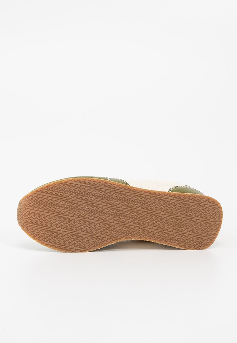 Soletta della scarpa con superficie testurizzata e decorata, dotata di una suola in gomma naturale e una parte superiore di colore chiaro con dettagli verdi.