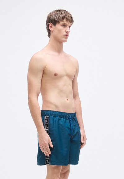 Τιρκουάζ μαγιό σόρτς με μαύρες πλαϊνές λεπτομέρειες, ελαστική μέση και κορδόνι. Ομαλή υφή και μήκος μέχρι το μέσο του μηρού.