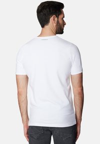 Biała koszulka z krótkim rękawem, okrągłym dekoltem i logo na plecach. Wykonana z gładkiego materiału, o dopasowanym kroju.