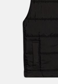 Gilet imbottito nero con una texture liscia e lucida. Presenta cuciture orizzontali e una tasca laterale, creando una silhouette elegante.