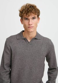 Grauer Strickpullover mit V-Ausschnitt und Kragen, lange Ärmel und weiche Textur, in taillierter Form. Minimalistischer Stil ohne Muster.