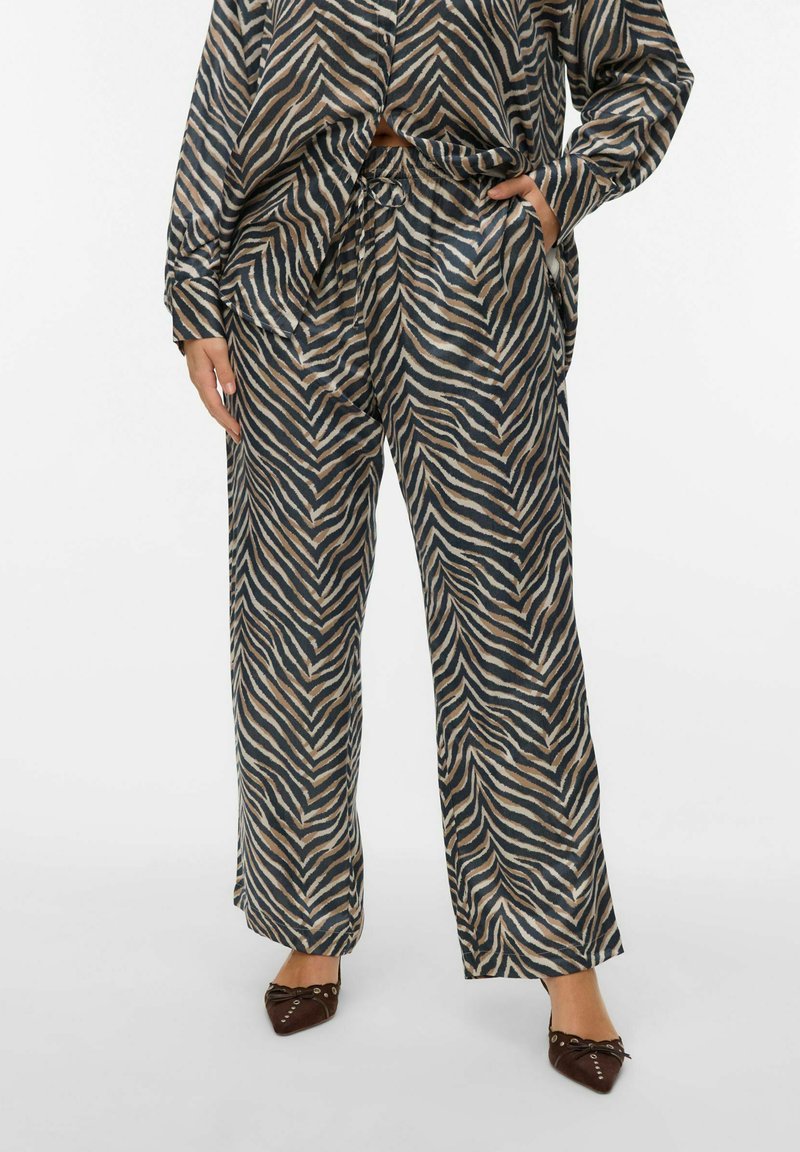 Long, loose-fitting pants in a wave pattern, featuring shades of navy, beige, and cream. Made of soft, lightweight fabric with an elastic waistband.