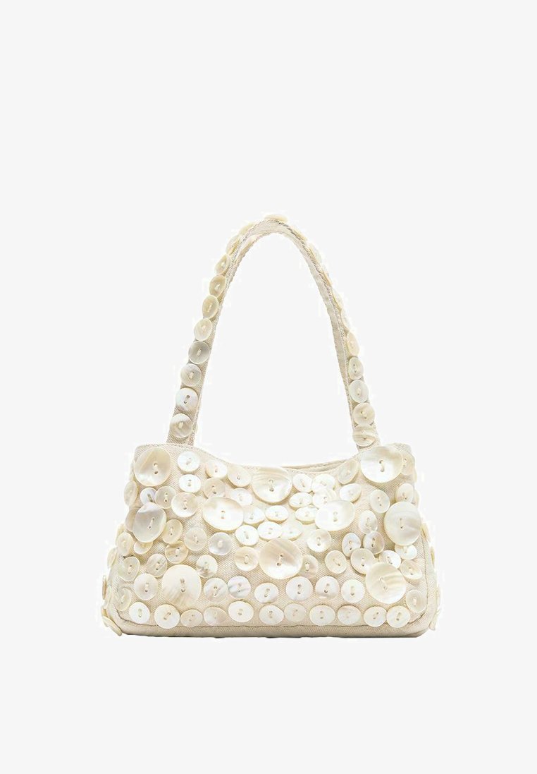 Petit sac à main crème avec plus de 50 boutons blancs de tailles variées couvrant le devant et la poignée sur un fond blanc uni.