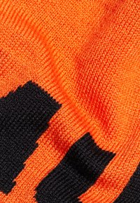 Tessuto lavorato a maglia con un motivo arancione brillante e nero. La texture appare liscia, con colori contrastanti disposti in un design audace.