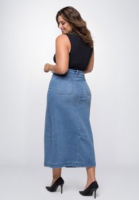 Lichte blauwe denimrok, van volledige lengte met een hoge taille, met achterzakken en een recht ontwerp. Duidelijke stiksels en een soepele textuur.