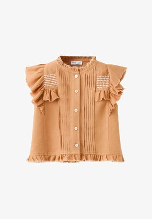 Blouse beige sans manches avec épaules volantées, plis verticaux sur le devant, boutons blancs et lignes blanches brodées sur le haut de la poitrine.