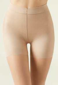 Beige shapewear-shorts med ett strukturerat stickat mönster, hög midja, sömlösa kanter och en slät finish på låren för en figurnära silhuett.