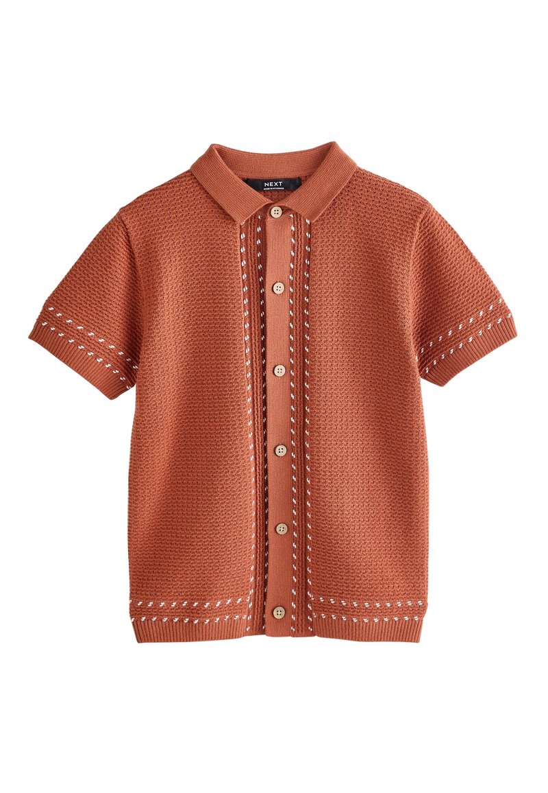 Polo a maniche corte di colore ruggine, con motivo a rilievo, bottoni sul davanti e cuciture a contrasto in bianco lungo le giunture.
