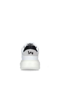 Sneaker bianca con tallone in suede grigio, accenti neri sulla linguetta e logo nero in rilievo. Presenta materiale sintetico liscio e suola spessa.