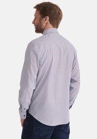 Herren Langarmhemd in Weiß mit einem blau-roten geometrischen Punktmuster. Mit klassischem Kragen und Knopfmanschetten.