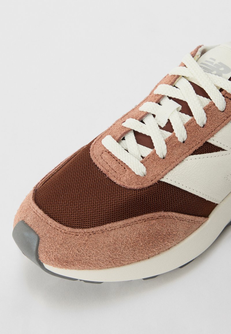 Baskets de course avec un dessus en daim brun et en maille, accents en cuir blanc et semelle beige. Comprend des lacets texturés et une pointe arrondie.