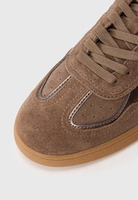 Braune Wildledersneaker mit einer Gummi-Sohle, ausgestattet mit einem eleganten Design, abgerundetem Zehenbereich und durchlöcherten Details entlang des Obermaterials.