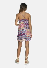 Vestido de verano con un estampado colorido, tirantes ajustables y espalda fruncida, que presenta diseños geométricos en púrpura, rosa y azul.