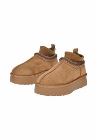Stivaletti alla caviglia in suede color tan con colletto in maglia a coste, cuciture decorative e suola in gomma spessa per maggiore altezza e grip.