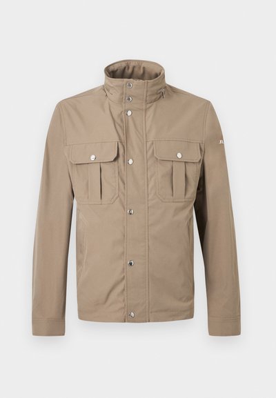 Veste beige pour homme avec col montant, boutons pression à l'avant, deux poches à rabat sur la poitrine avec boutons, et manches longues.