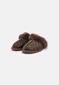 Pantofole con stampa leopardata, dotate di un risvolto in pelliccia sintetica marrone, tomaia in tessuto morbido e suola in gomma marrone. Texture liscia con motivi a contrasto.