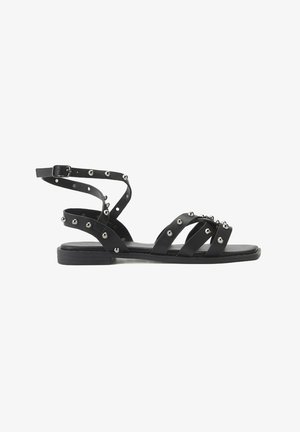 Zwarte sandalen met bandjes, versierd met zilveren studs, vlakke zool en een verstelbare enkelband. Bevat meerdere gekruiste leren bandjes voor ondersteuning.