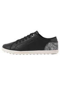 Black sneaker with a textured fabric accent on the heel, rubber sole, flat laces, and logo detail on the side. Smooth leather upper.